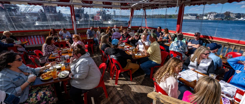 Guests dining on a waterfront deck at Hit the Decks